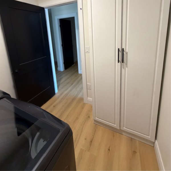 Farwes laundry with white millwork closets, black doors, and oak flooring