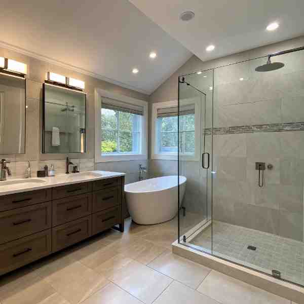 Farwes bathroom with a freestanding tub, glass shower, and wood vanity