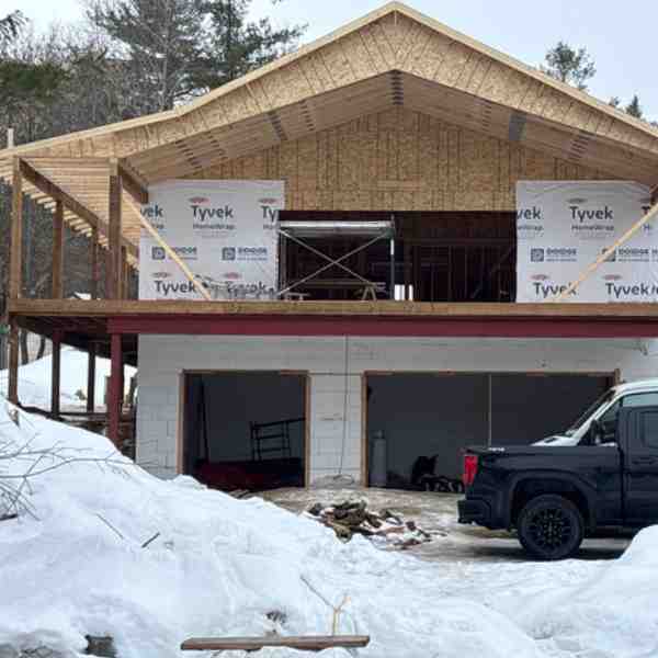 Farwes bungalow framed in winter with Tyvek wrap and a two-car garage