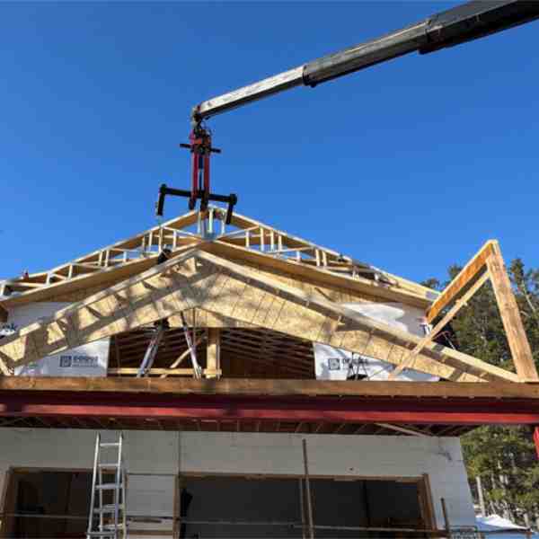 Crane setting roof trusses on a Farwes house