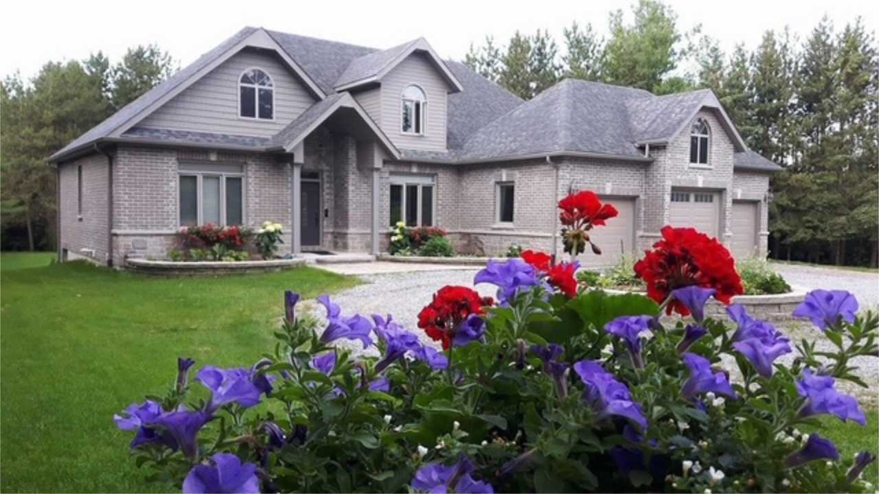 Grey brick Farwes custom home with a two-car garage and garden — the work we build across Northumberland, Durham, and the Kawartha Lakes