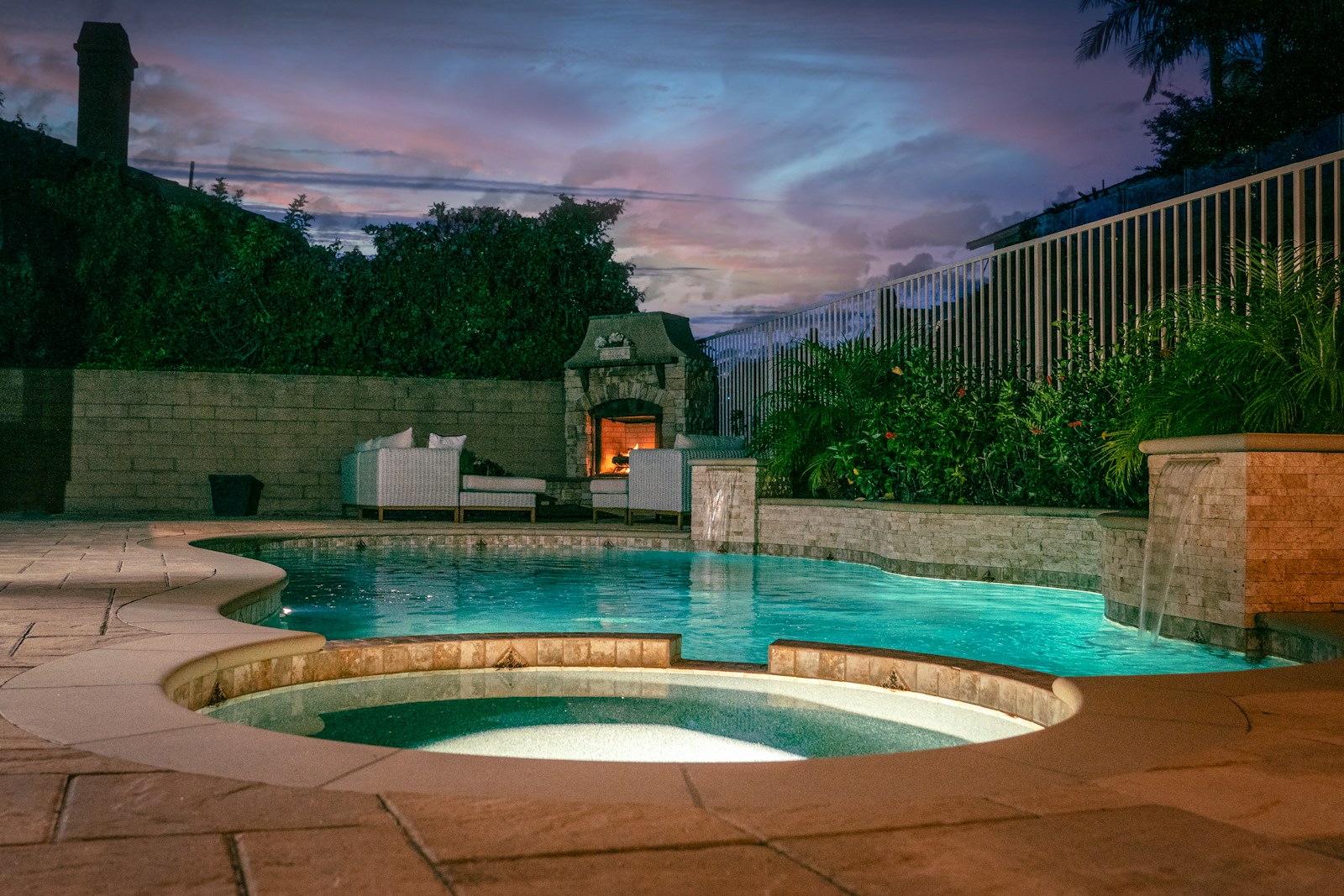 Pool with raised spa, fire feature and landscaped walls at dusk
