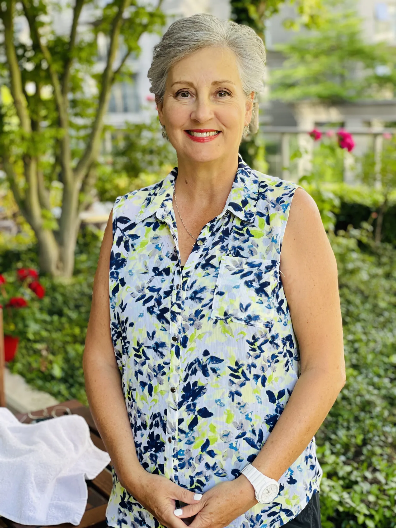 Melinda Freitas, Registered Clinical Counsellor, smiling outdoors in a garden wearing a navy and white floral sleeveless blouse