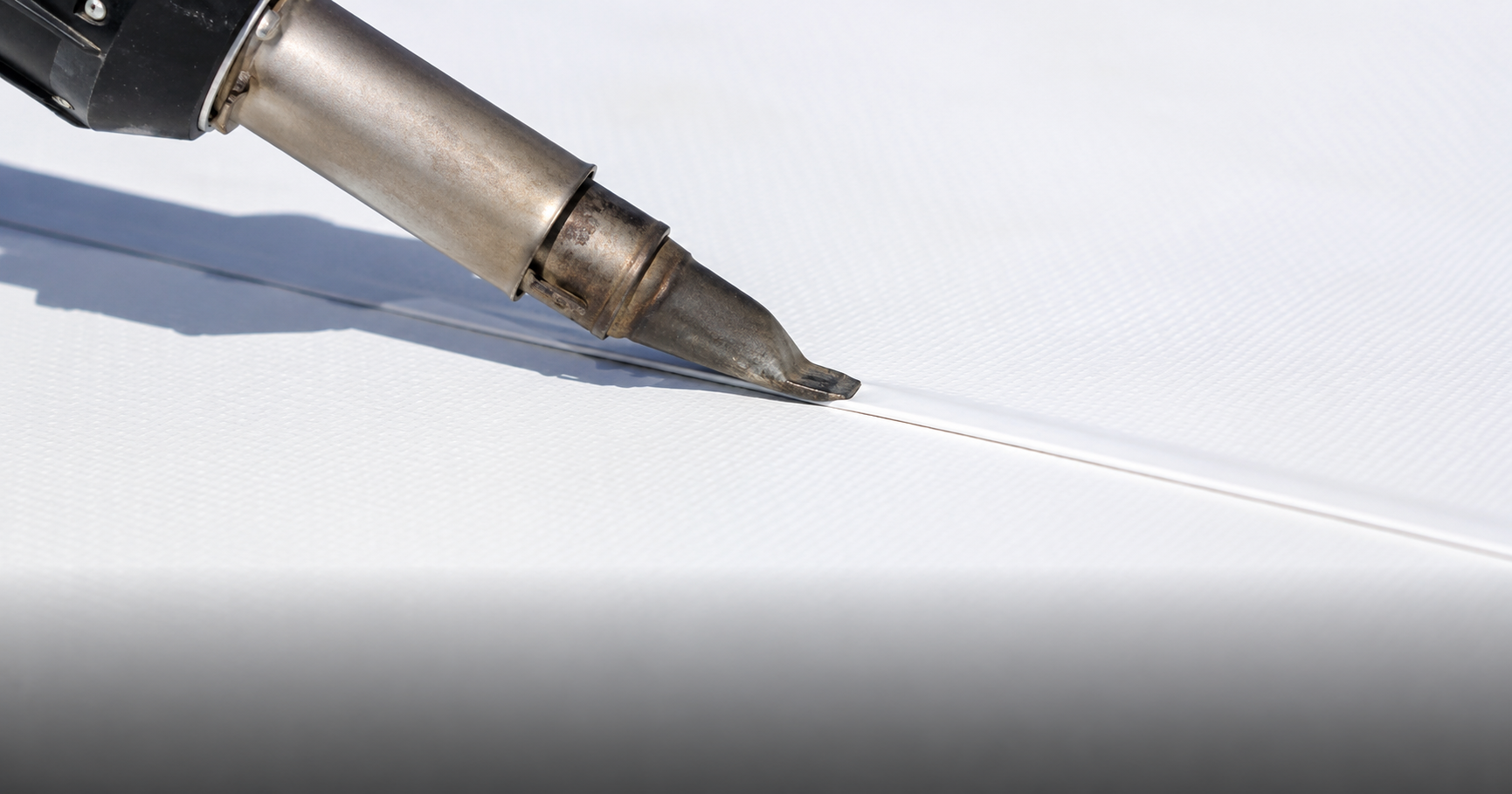 Close-up of TPO membrane seams being heat-welded showing the precision bond