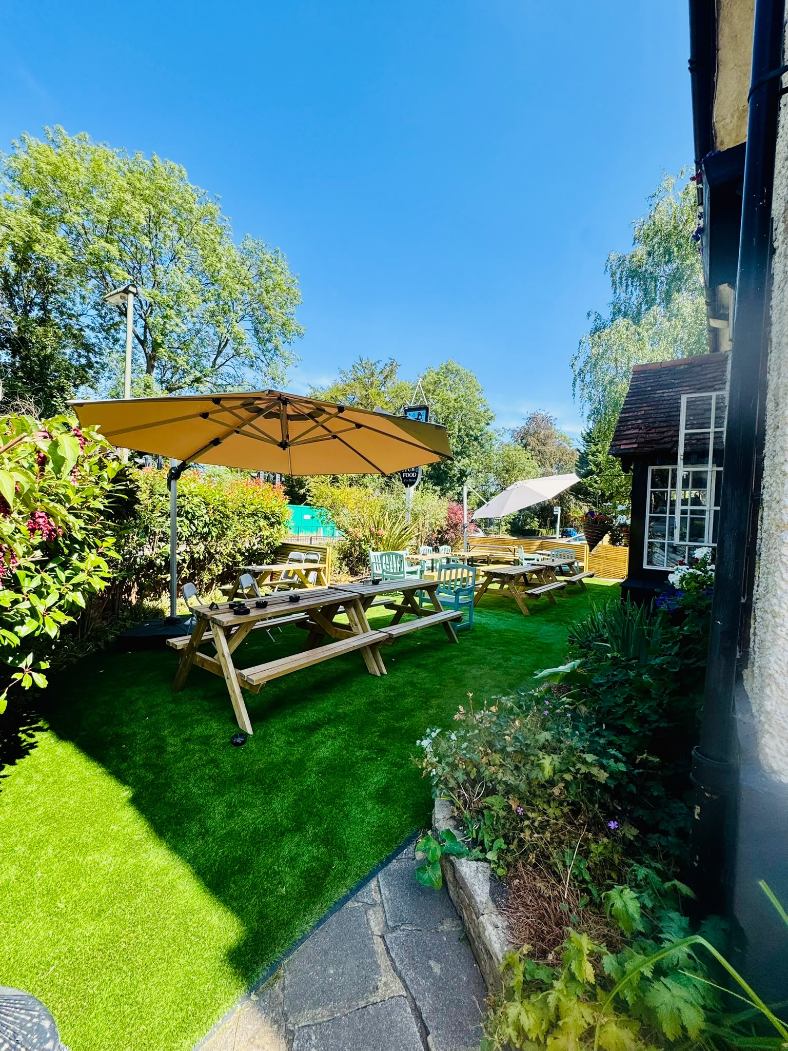 The garden at The Anchor Bookham on a sunny day, with the white cottage exterior