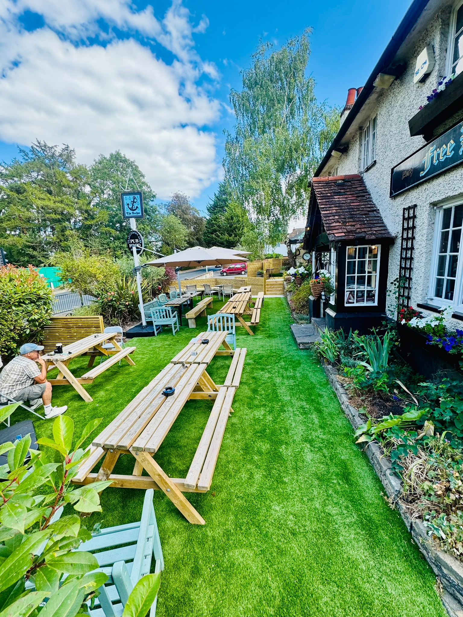 The Anchor Bookham pub beer garden with parasols and white cottage exterior in Surrey