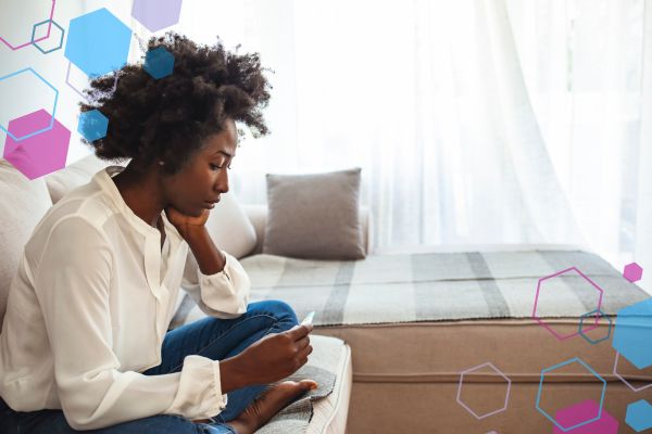 Person sitting and looking at a pregnancy test with a thoughtful expression, reflecting uncertainty in early pregnancy when symptoms are not yet noticeable.