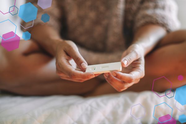 Person holding a pregnancy test at around 5–7 weeks pregnant when symptoms may still be mild or absent.