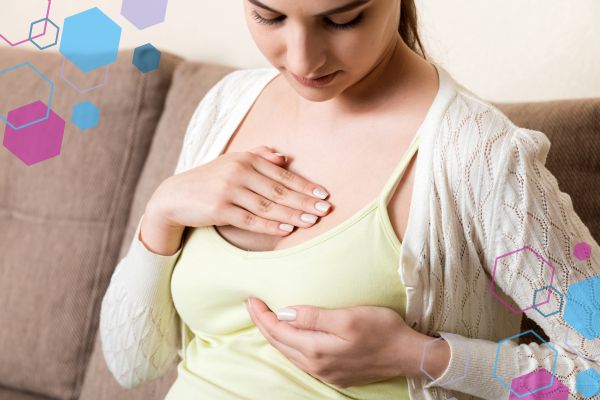 Pregnant person holding their breast while looking down, illustrating breast tenderness during early pregnancy.