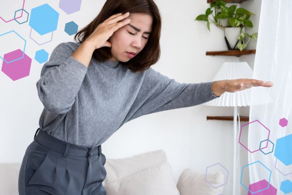 Person standing and holding their head while steadying themselves, illustrating dizziness or feeling faint in early pregnancy.