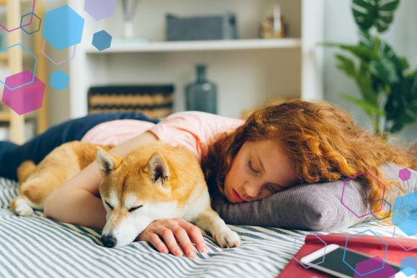 Person lying on a bed, next to a dog, looking exhausted, representing low energy and fatigue in early pregnancy.