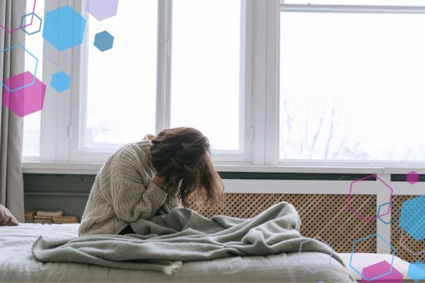 Headaches in early pregnancy. Person sitting on a bed with their head in their hands, illustrating headache pain or discomfort in early pregnancy. Headaches in early pregnancy. Person sitting on a bed with their head in their hands, illustrating headache pain or discomfort in early pregnancy.