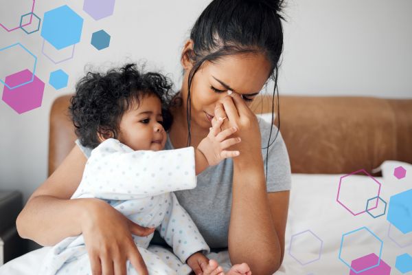 Parent holding a baby while pressing their forehead, representing managing headaches during early pregnancy while caring for a child. Parent holding a baby while pressing their forehead, representing managing headaches during early pregnancy while caring for a child.