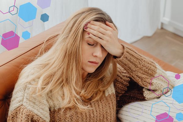 Person sitting on a sofa with a hand on their forehead, illustrating headache discomfort in early pregnancy. Person sitting on a sofa with a hand on their forehead, illustrating headache discomfort in early pregnancy.