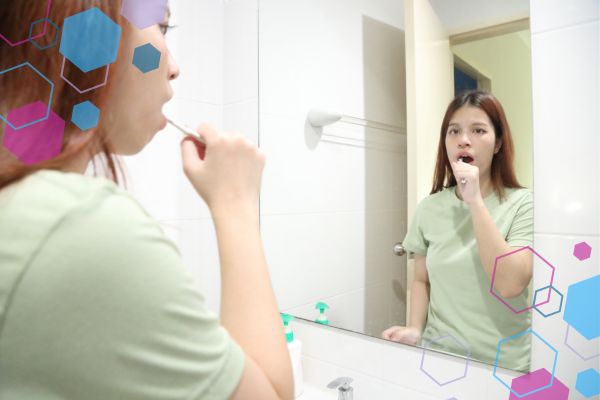 Person brushing their teeth in front of a mirror, illustrating gag reflex sensitivity that can occur in early pregnancy. Person brushing their teeth in front of a mirror, illustrating gag reflex sensitivity that can occur in early pregnancy.