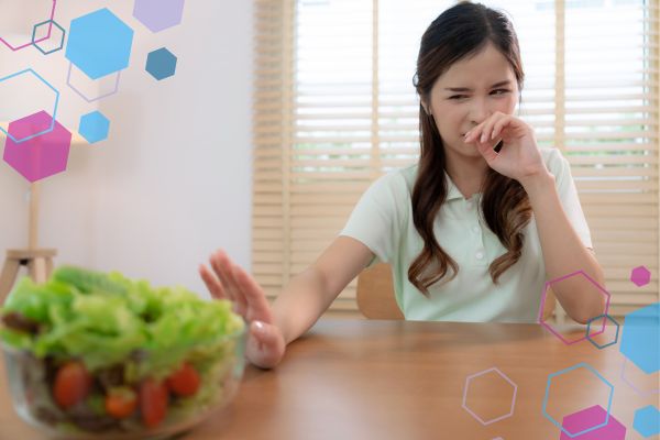 Person turning away from food due to strong taste or smell, representing metallic or altered taste in early pregnancy around 5–9 weeks. Person turning away from food due to strong taste or smell, representing metallic or altered taste in early pregnancy around 5–9 weeks.