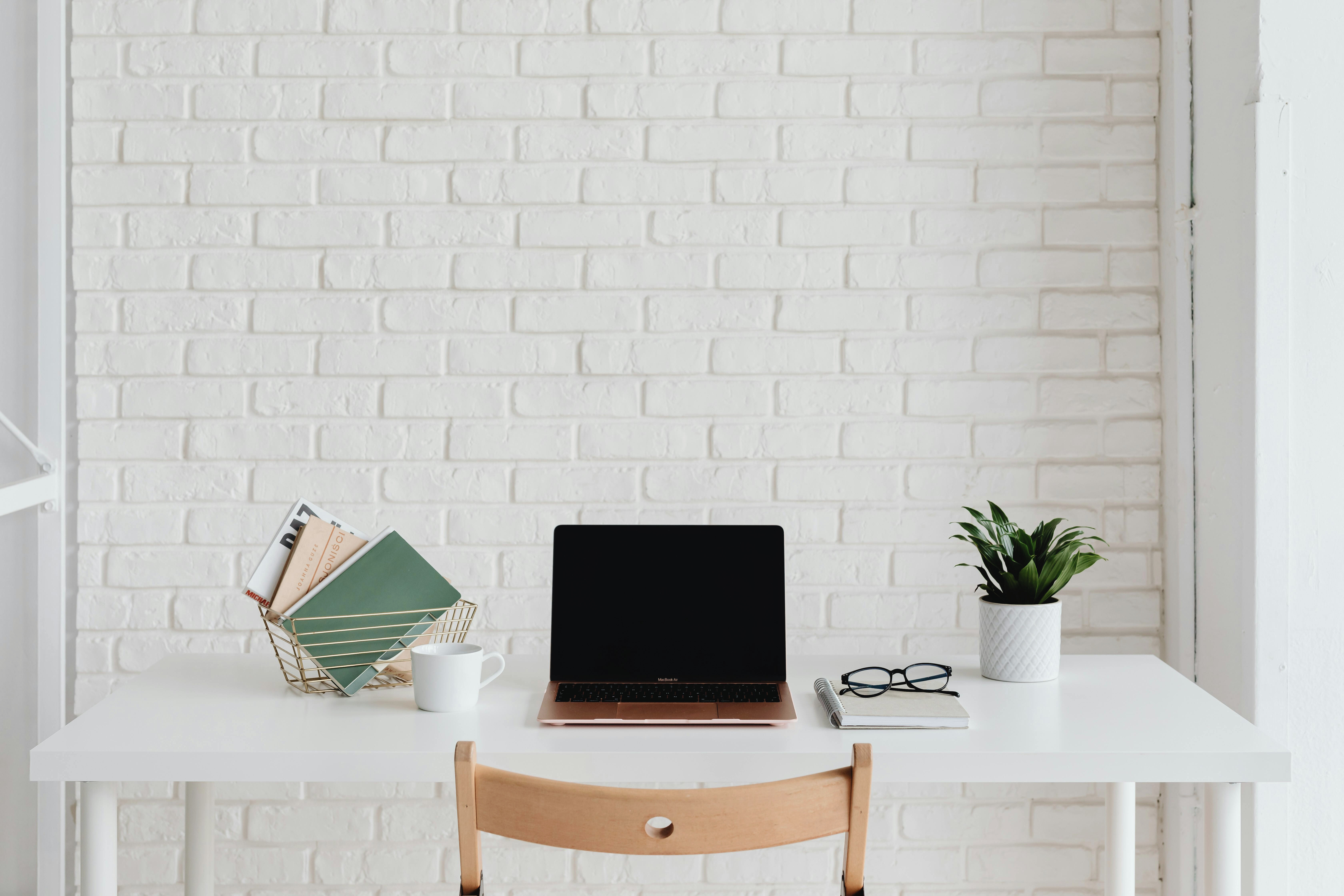 Computer desk against a white painted brick wall