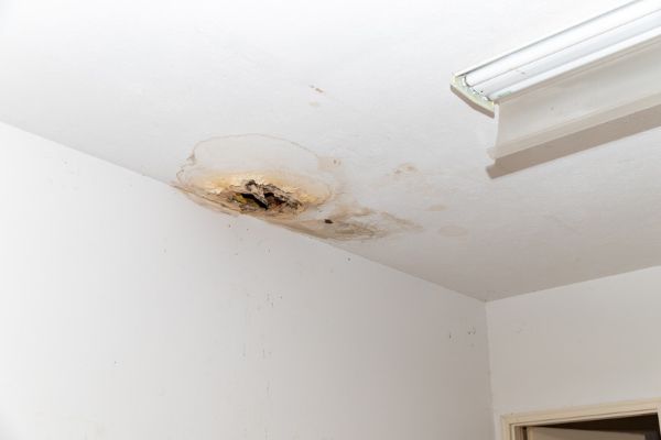 Sagging, water-damaged ceiling above an empty room before emergency roof repair. Sagging, water-damaged ceiling above an empty room before emergency roof repair.
