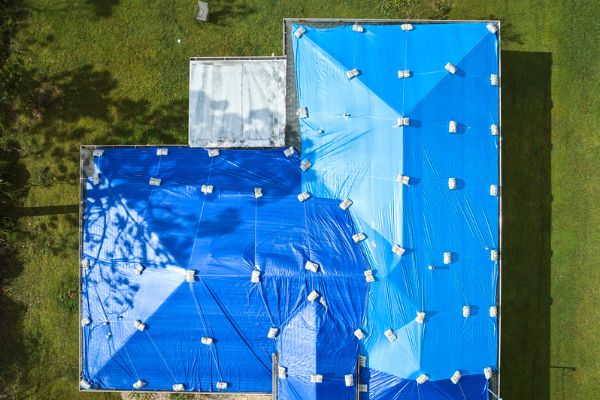 Secured roof tarp covering storm damage during emergency roof repair. Secured roof tarp covering storm damage during emergency roof repair.