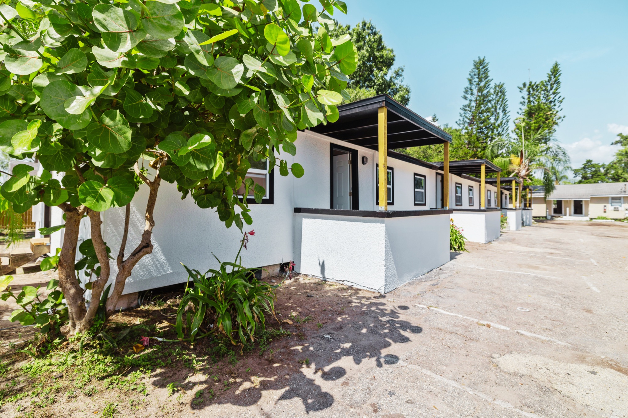 The 24-unit garden-style apartment building in Tampa Heights, Florida, after renovation: white rendered walls, black trim and new covered entryways.