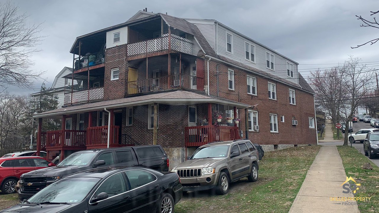 Empire Street, Wilkes-Barre, as acquired: a three-storey brick apartment building with worn red porches, mismatched balcony rails and tenants' belongings stacked on the decks.