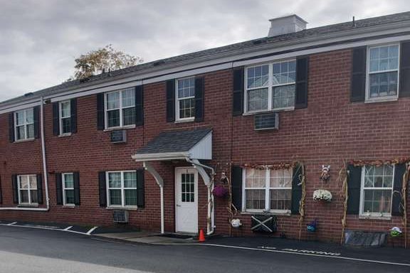 One of the brick two-storey apartment buildings at 173 E Tioga Street, Tunkhannock, with a covered entrance and wall air conditioners.