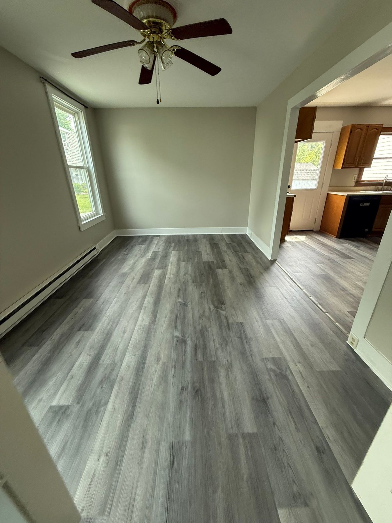 A finished living room at 176 Bridge Street: fresh white walls, new grey wood-look flooring and daylight from two windows.