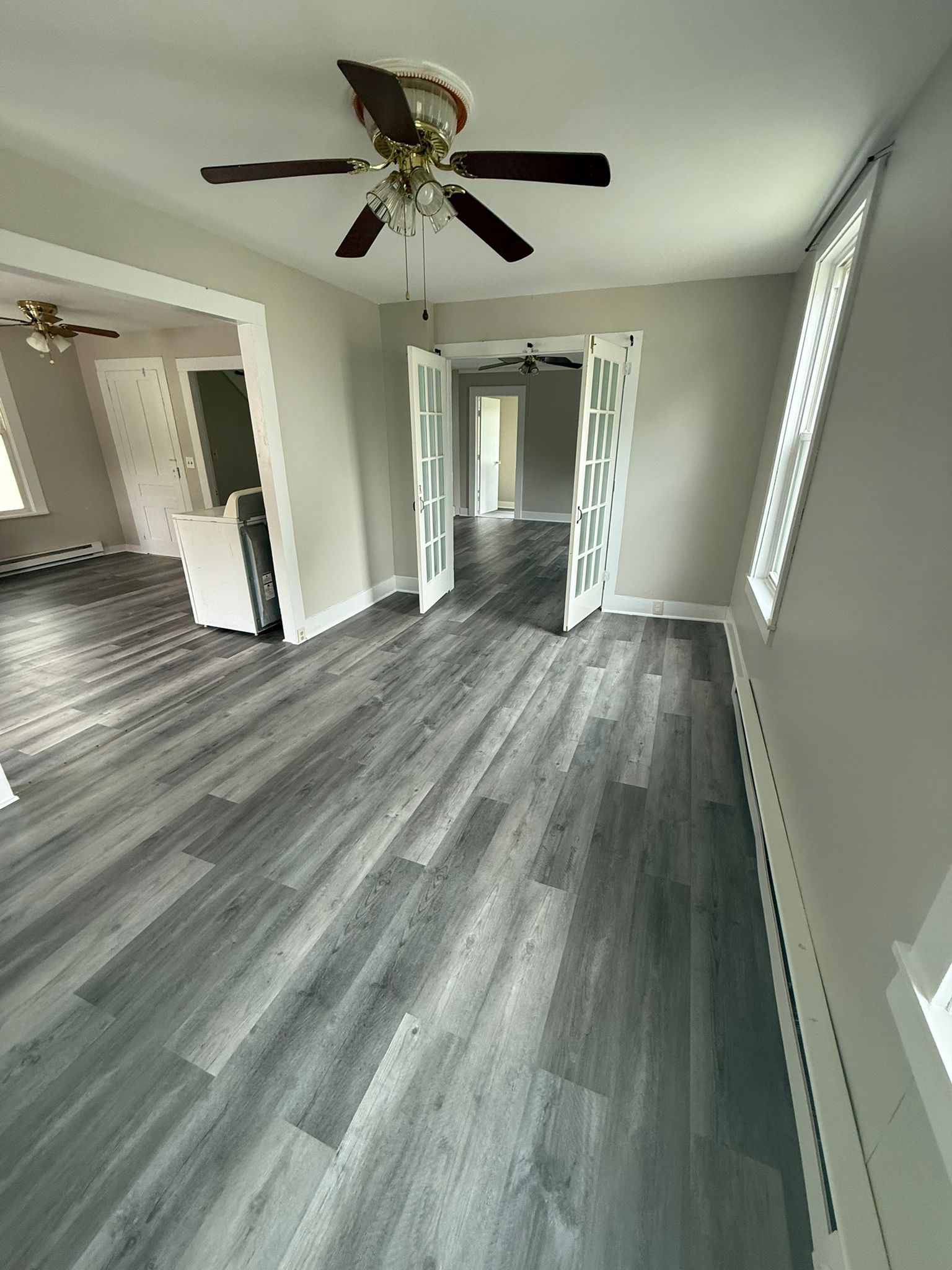 A finished reception room at 176 Bridge Street, looking through glazed double doors into the room beyond, with new grey wood-look flooring throughout.