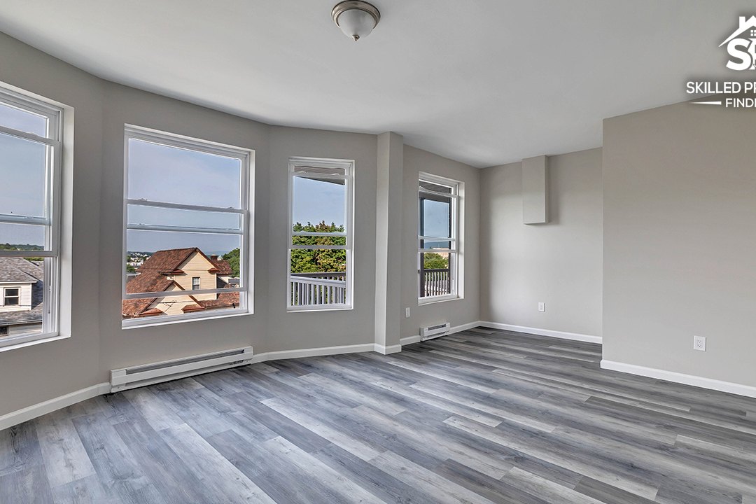 Inside the same bay at Vine Street: a finished room with a run of windows on three sides, fresh walls and new grey wood-look flooring.