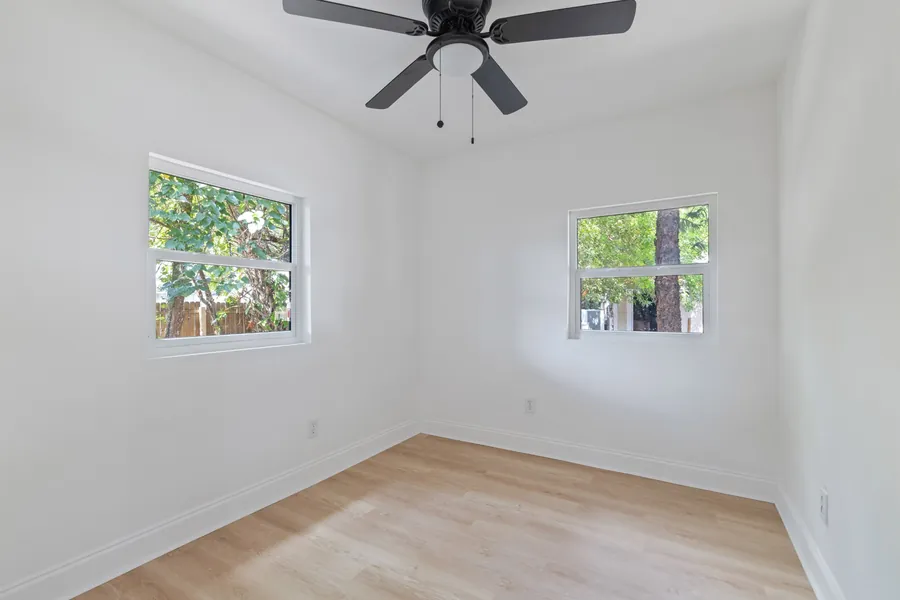 A renovated bedroom at Drew Park: white walls, two new windows, a ceiling fan and light wood-look flooring.