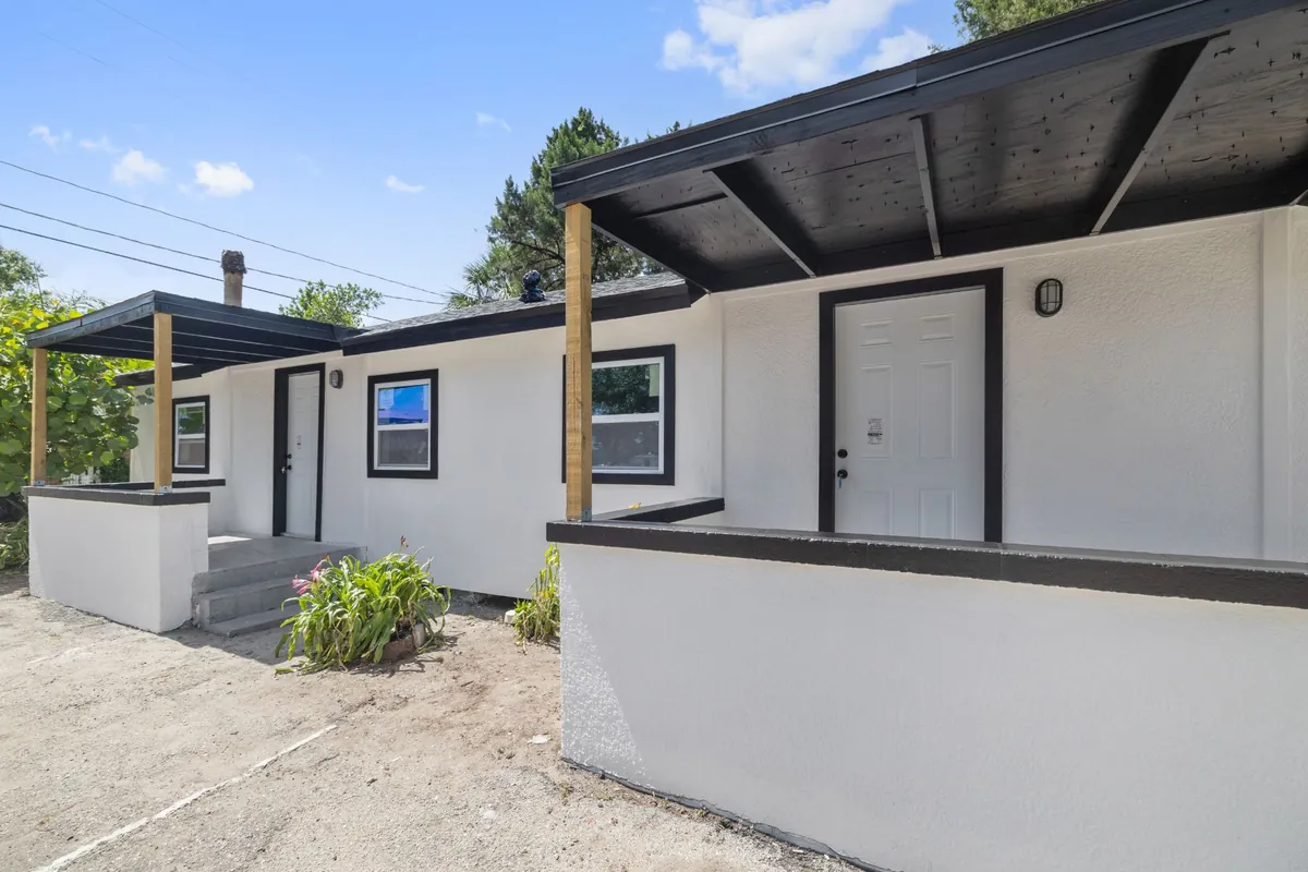 Part of the Drew Park property on North Hubert Avenue, Tampa, as it is now: white rendered walls with black trim, low porch walls with a black cap, and covered entries on timber posts.