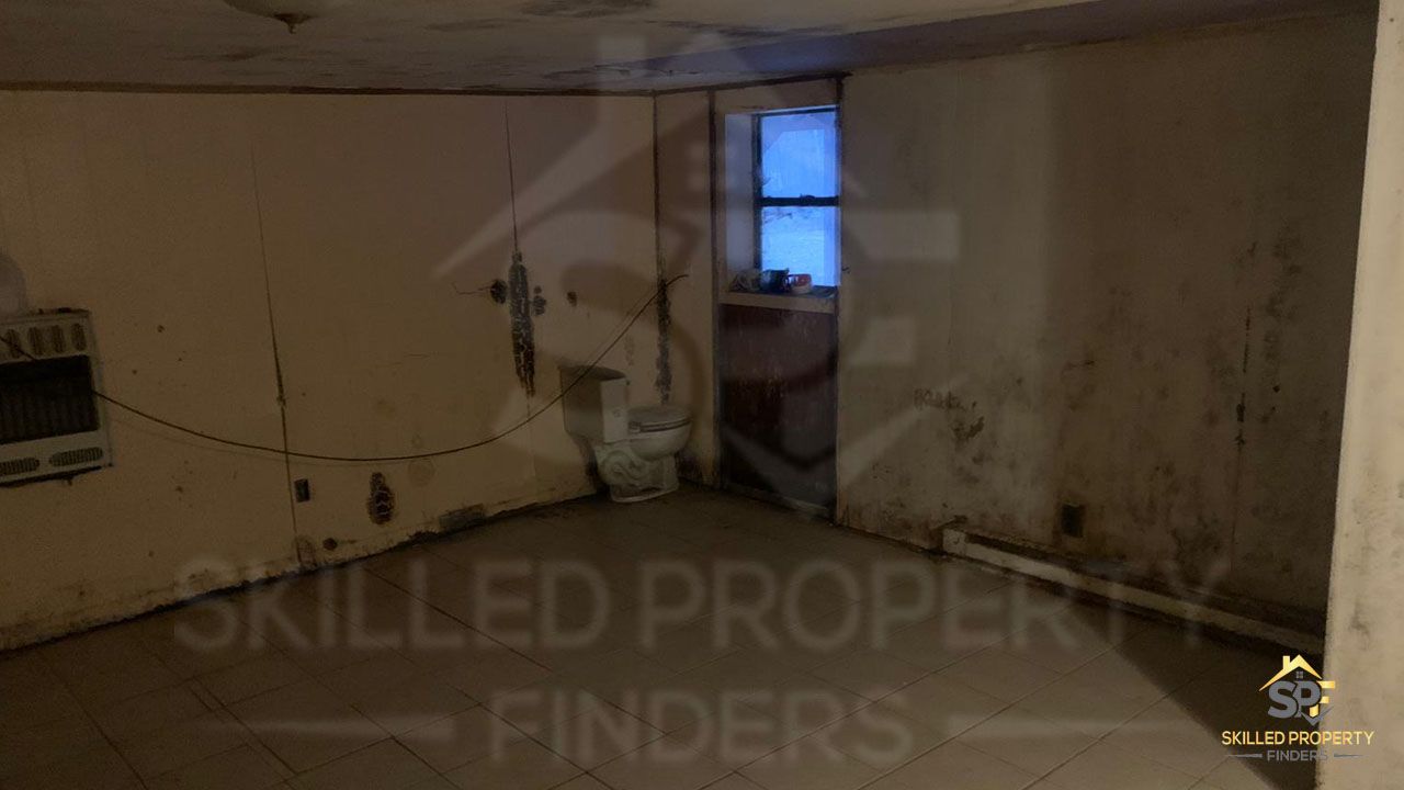 A Northeast Pennsylvania basement as we found it: stained walls, an exposed toilet, a space heater and years of deferred maintenance.