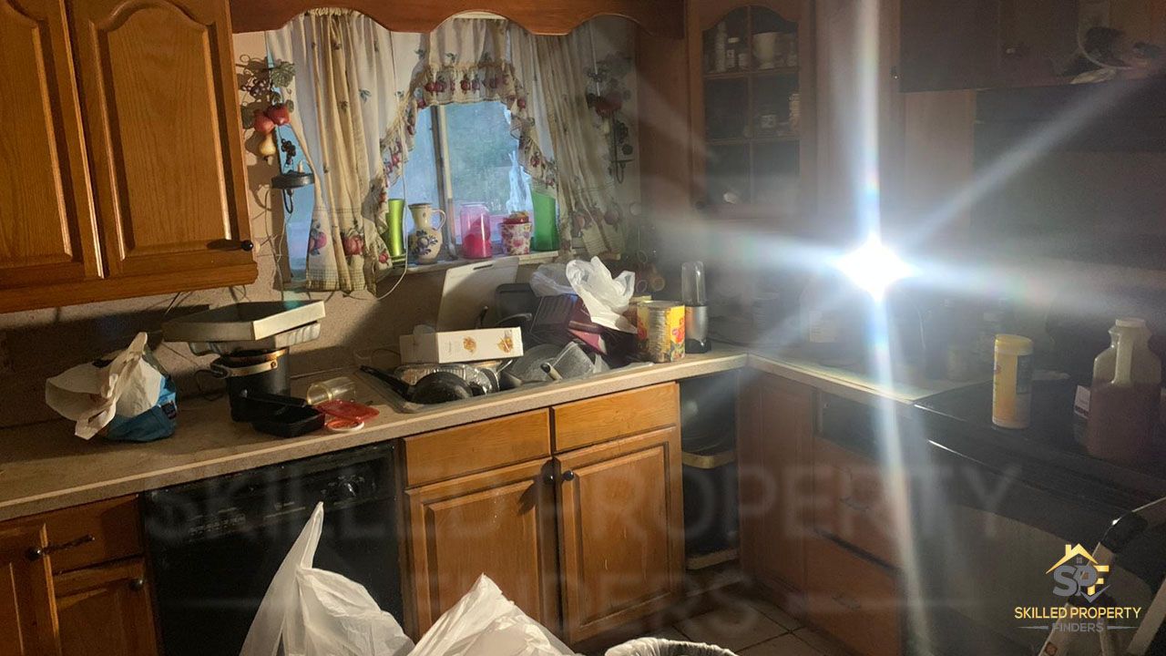 A Northeast Pennsylvania kitchen at acquisition: dated oak cabinets, worn laminate counters and years of clutter left by the previous ownership.