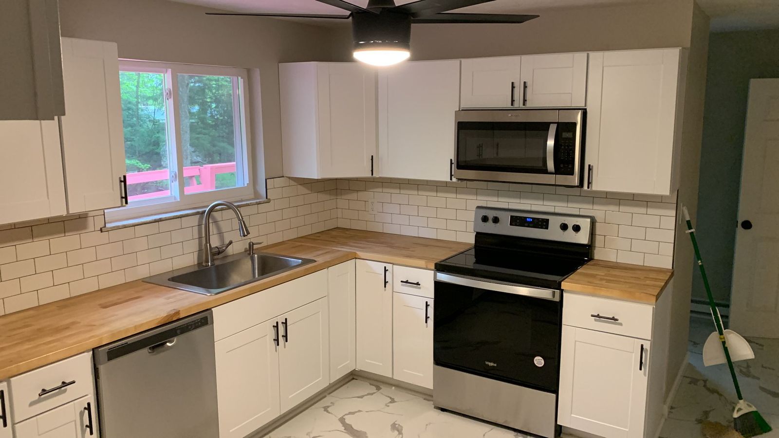 The same Northeast Pennsylvania kitchen rebuilt: white shaker cabinets, butcher-block counters, subway tile backsplash and new stainless appliances.