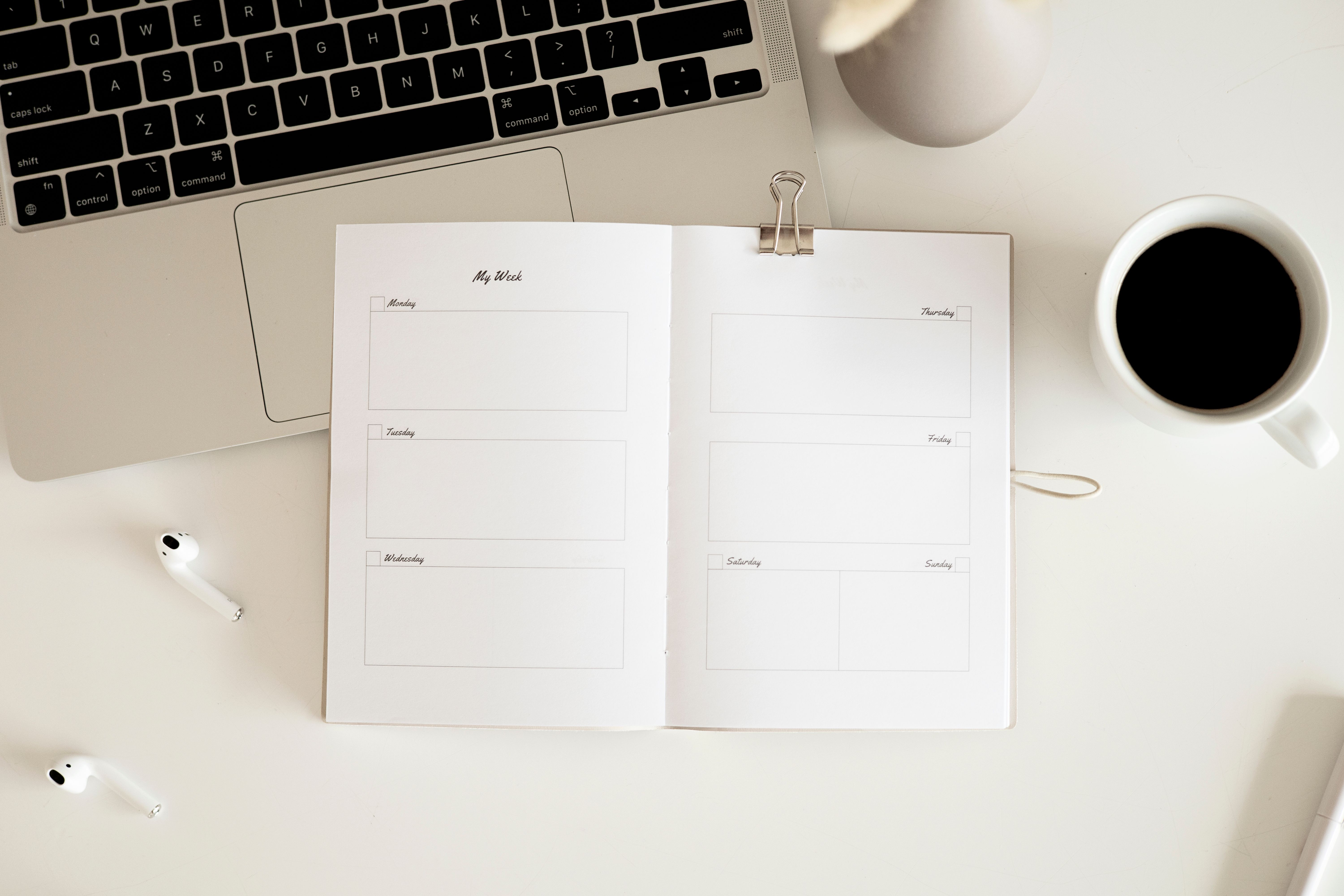 Open planner beside a laptop and coffee on a bright desk