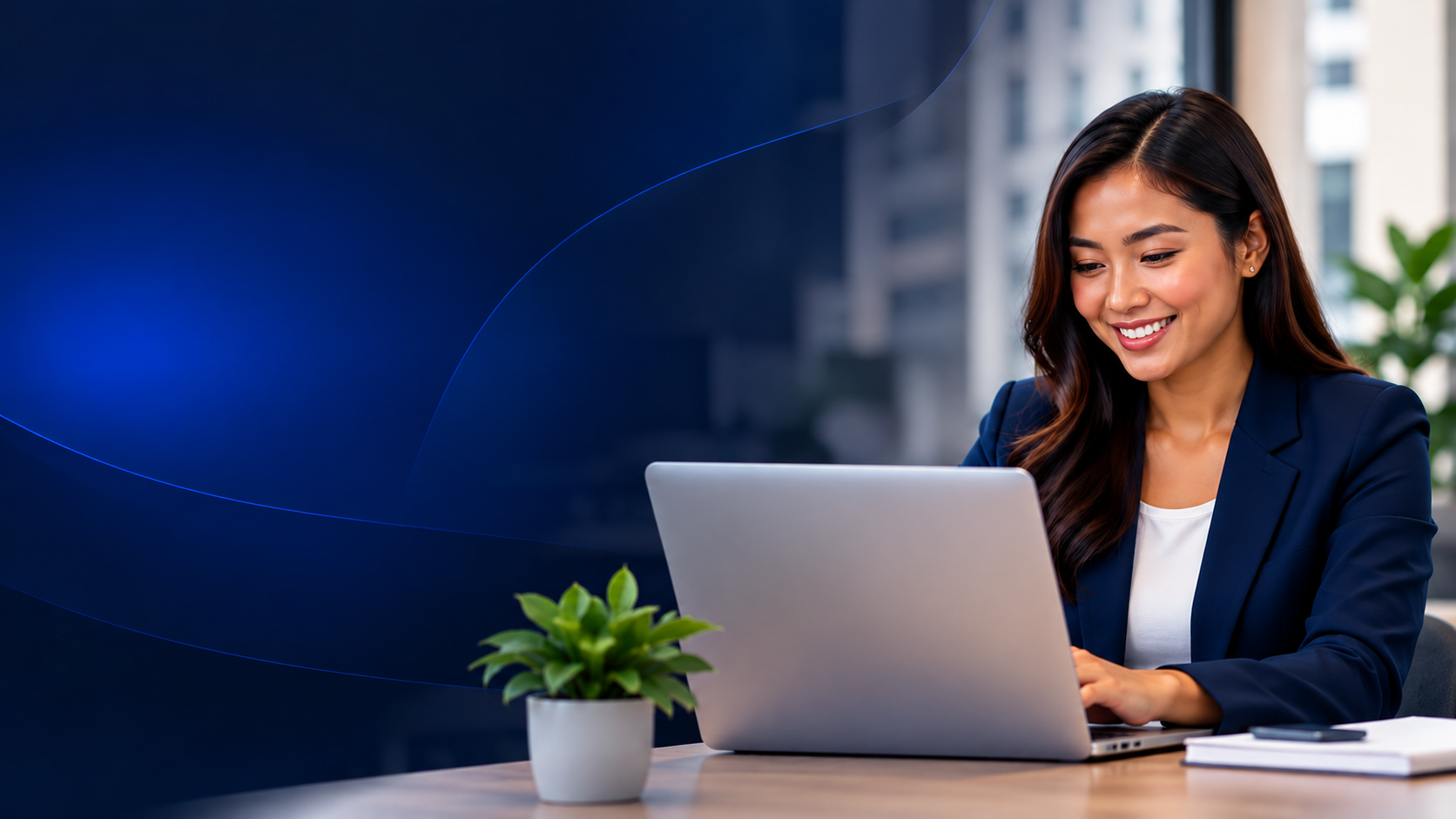 Smiling Filipino professional in a navy blazer working on a laptop at a desk