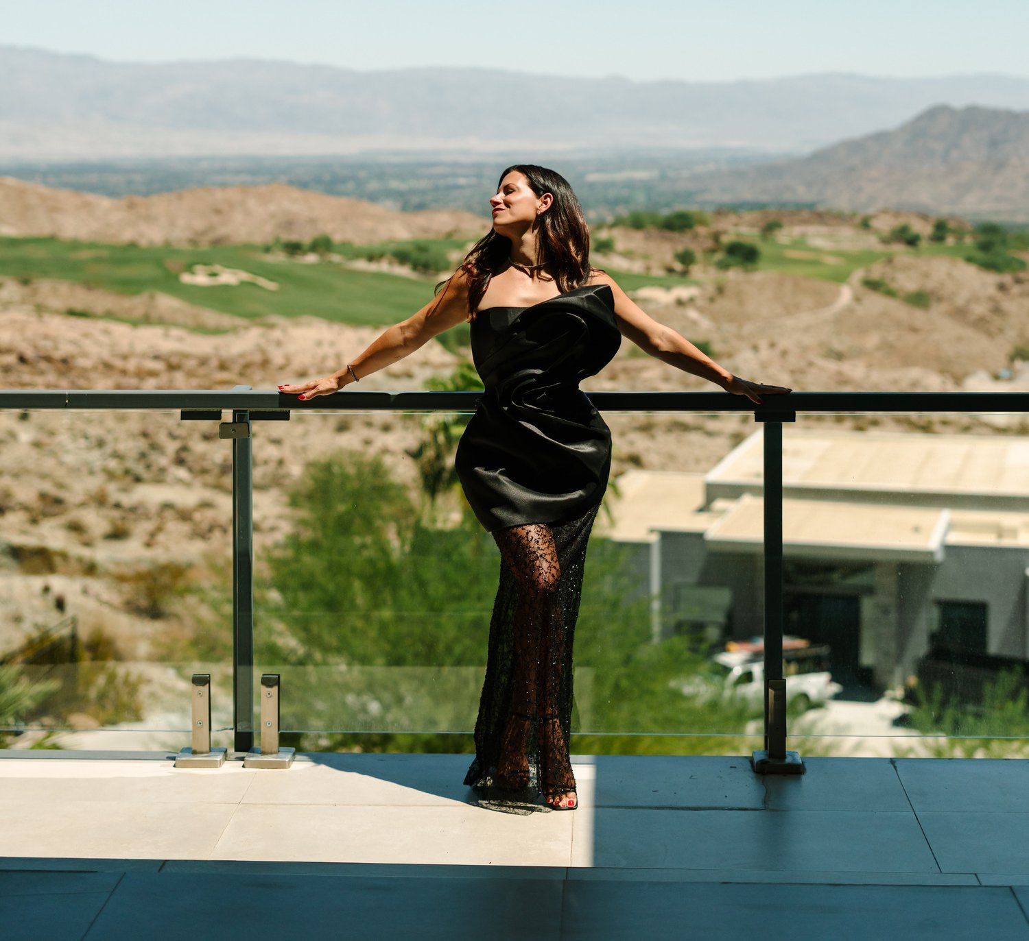 Stephanie on the terrace at the desert house, arms stretched along the rail