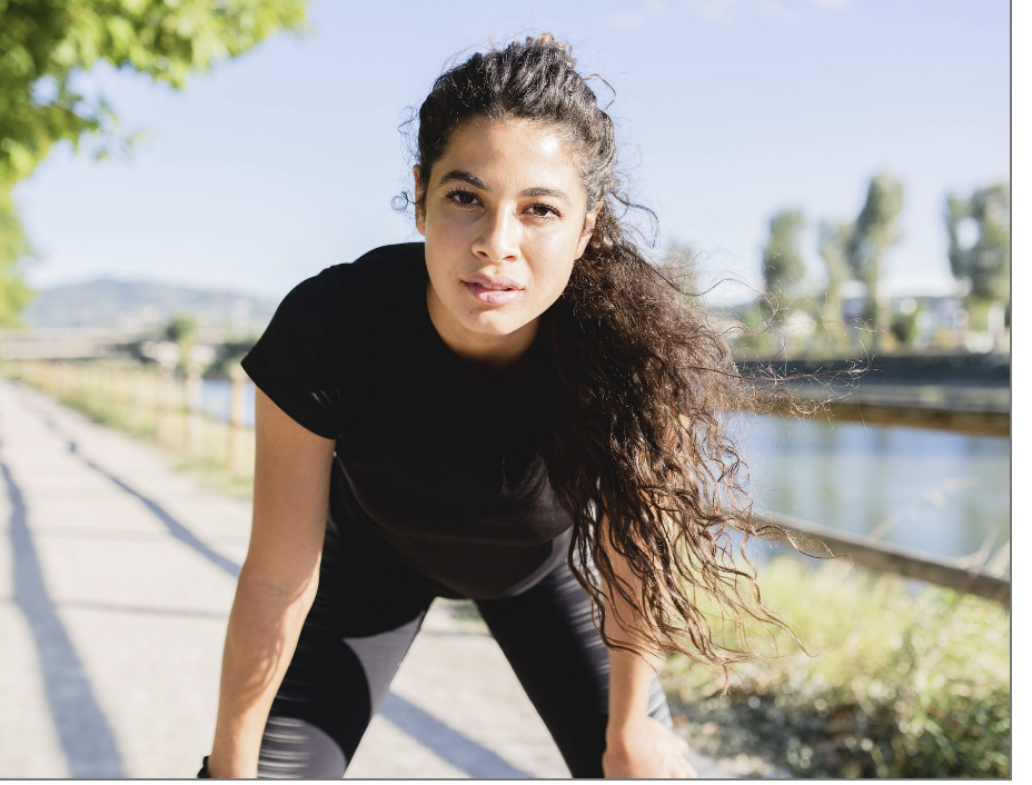 Woman outside holding her knees and bent over, looking at camera. Woman outside holding her knees and bent over, looking at camera.