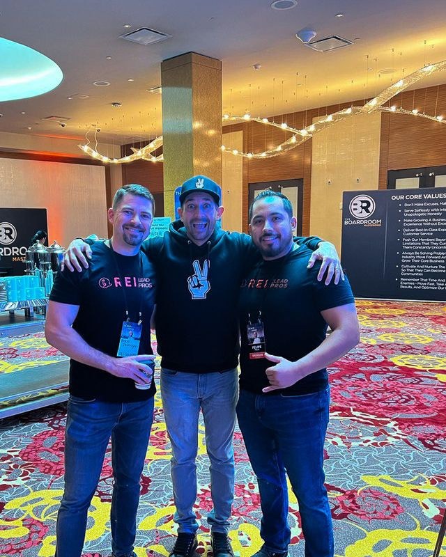 Anton with two men at a conference, one making a peace sign