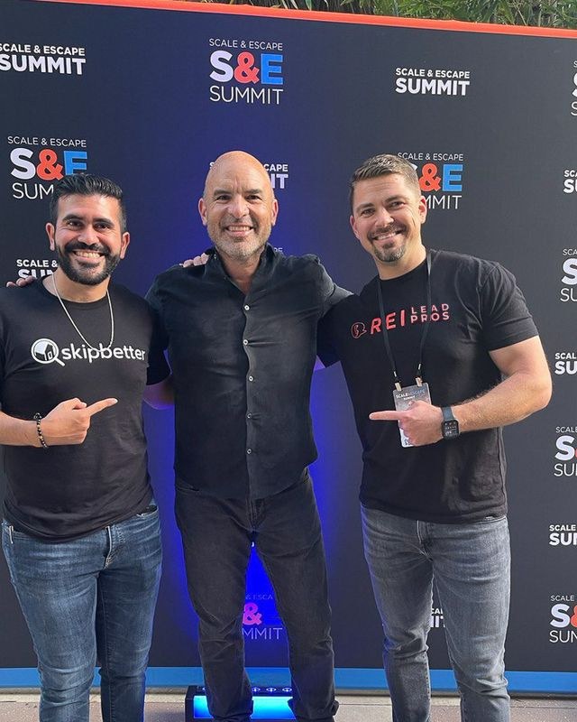 Anton with two other men in front of the Scale and Escape Summit backdrop