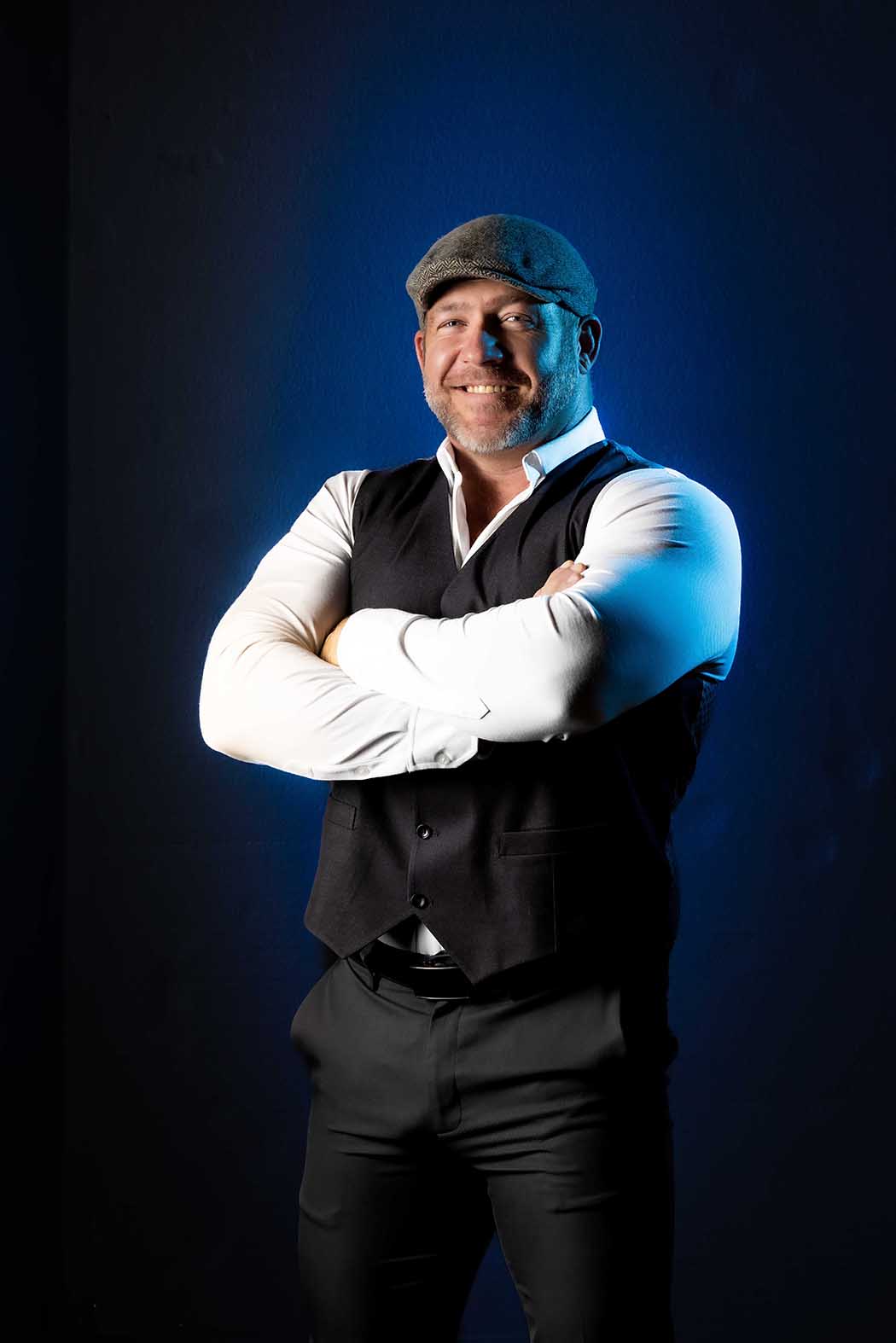 Confident man in stylish formal attire posing against a dramatic blue background, professional portrait photography in Colorado Springs studio