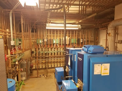 Complex heating system setup with multiple boilers and extensive piping in a mechanical room.