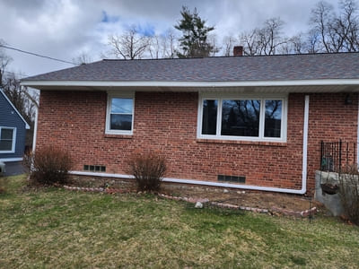 Exterior view of a brick house with visible ventilation, part of a residential heating and cooling system.