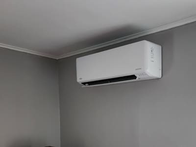 Modern wall-mounted air conditioning unit in a room with gray walls, ensuring optimal indoor climate control.