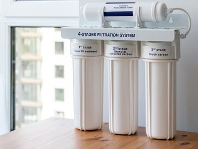 4-stage water filtration system placed on a countertop, designed for home use to provide purified water.