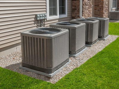 Row of outdoor heat pump units installed outside a residential building, ensuring efficient heating and cooling.