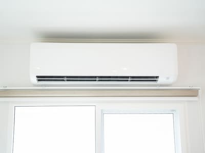 Wall-mounted air conditioning unit above a window, providing efficient cooling for the room.