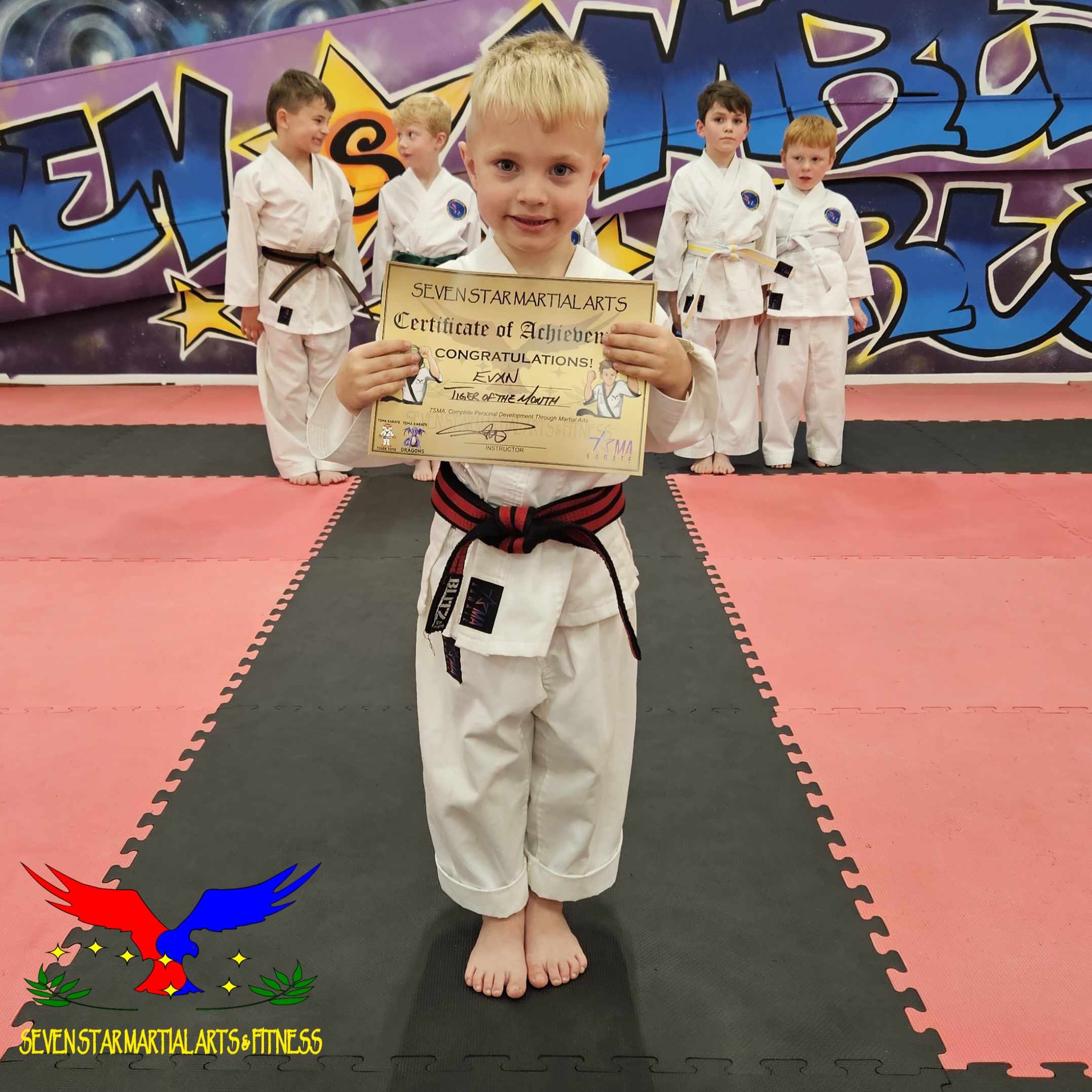 child age 5 with karate certificate celebrating success and development in front of the class of other children similar age