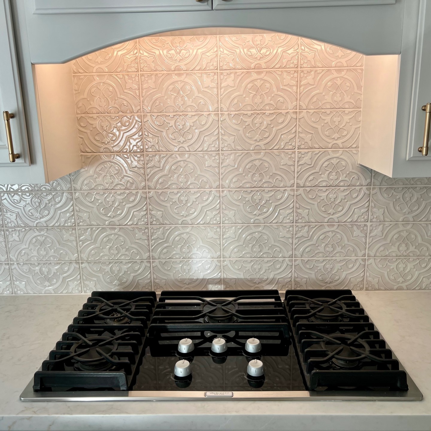 Gas cooktop with arched hood and tile backsplash — Niche Construction