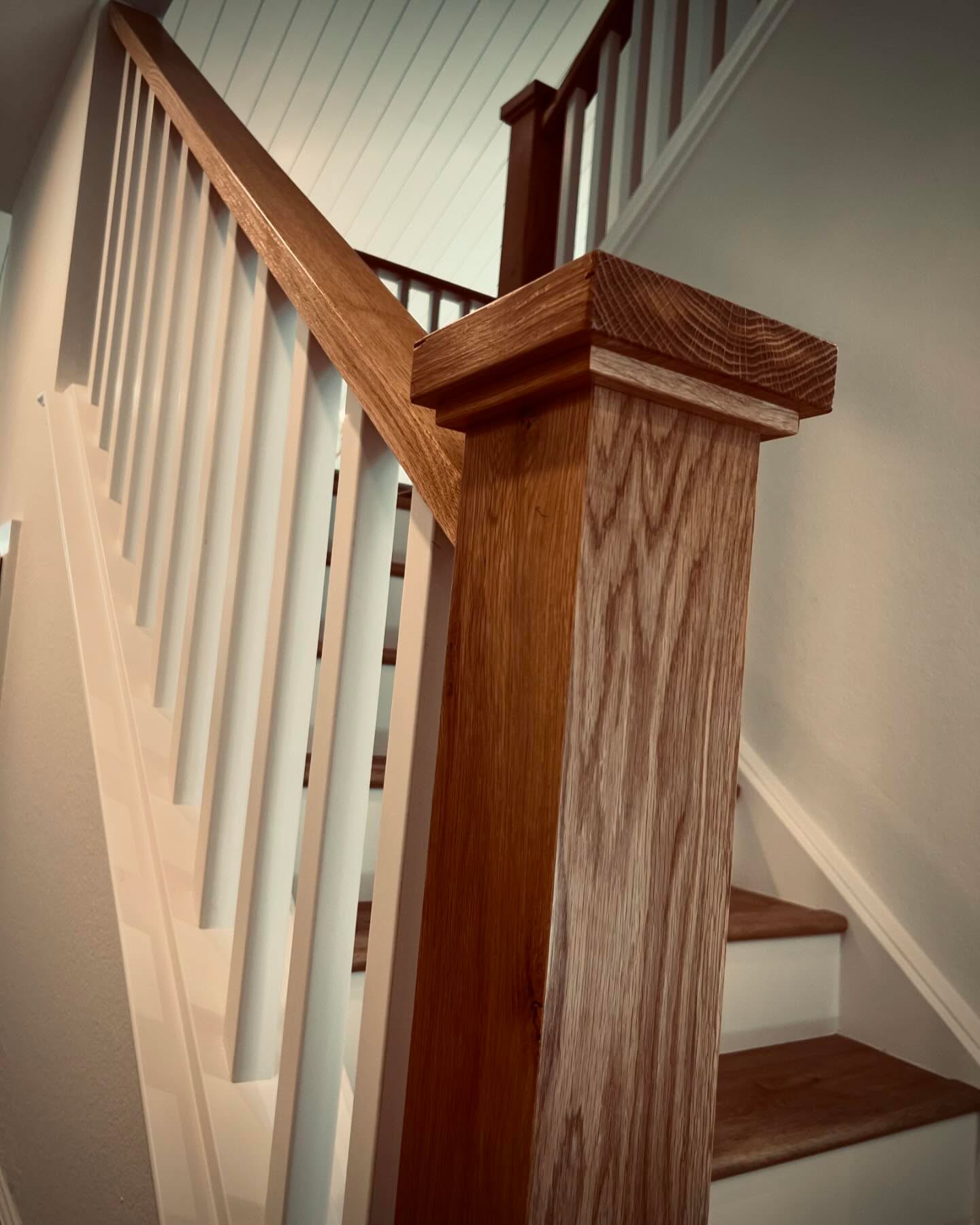 Staircase with wood handrail and white balusters — Niche Construction